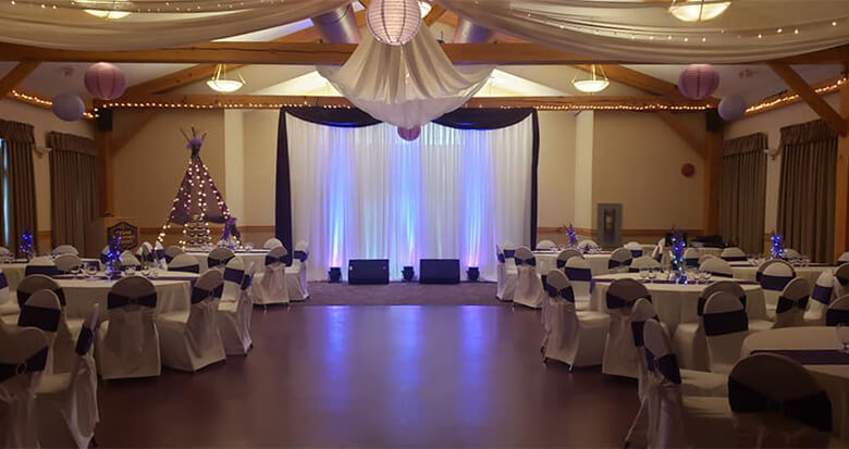 Cedar Meadows Spa & Resort A room at Cedar Meadows Resort & Spa set up for a wedding reception with purple and white decorations. - Timmins, Ontario