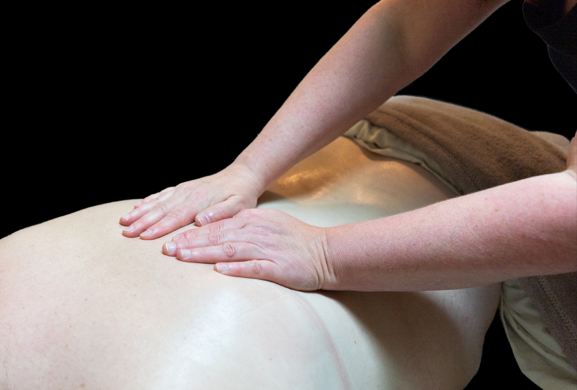 Cedar Meadows Spa & Resort Two hands performing a massage on a person's back with a towel partially covering their lower body. - Timmins, Ontario