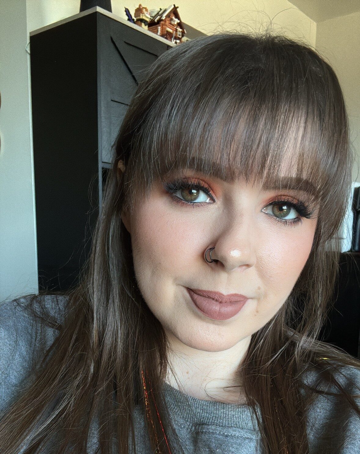 Cedar Meadows Spa & Resort A woman with long brown hair and bangs, wearing makeup and a grey sweatshirt, looks at the camera in a well-lit indoor setting. - Timmins, Ontario