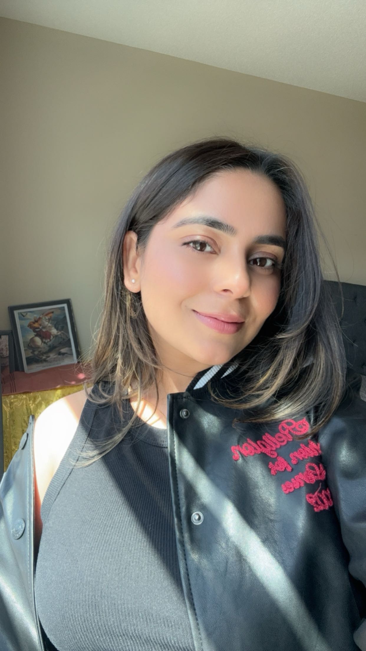 Cedar Meadows Spa & Resort A woman with shoulder-length brown hair takes a selfie indoors, wearing a black jacket and top. Sunlight streams in from the side, and framed art is visible in the background. - Timmins, Ontario